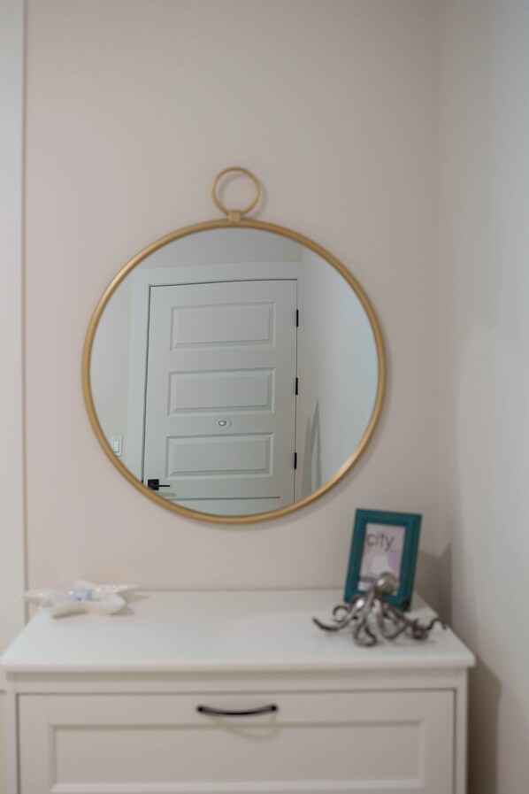 A white dresser with a mirror above it, a door in the reflection, and a small octopus decoration on the dresser. - Beautiful Bungalow - Steps from Okanagan Lake! Luxurious and family-friendly. (Kelowna)
