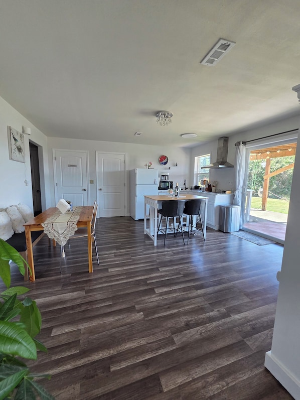 Una cocina amplia con comedor, muebles blancos y un ventanal grande.