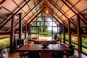 A spacious dining area with a large table, chairs, and a view of the outdoors through large windows.