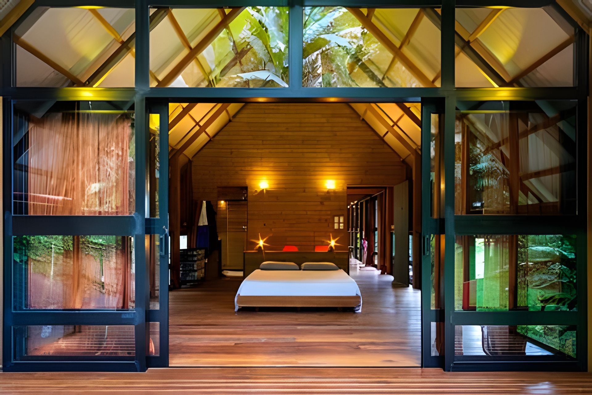 Um quarto espaçoso com uma cama grande, piso de madeira e teto inclinado com claraboias.