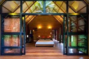 A spacious bedroom with a large bed, wooden flooring, and a sloped ceiling with skylights.
