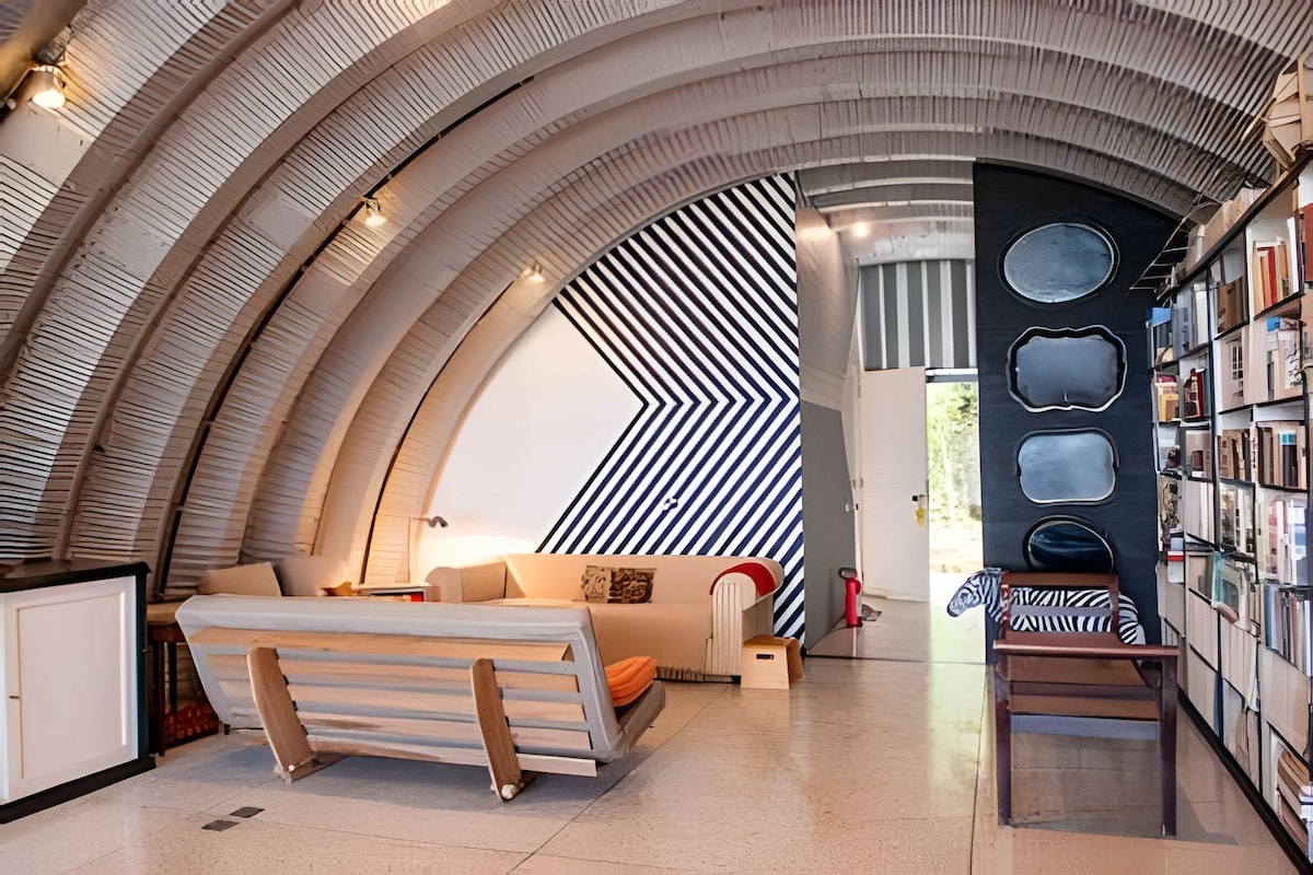 Ein modernes Interieur mit gewölbter Decke, einer Couch, einem kleinen Tisch und einem Bücherregal.