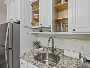 A kitchen with white cabinets, a stainless steel sink, and a granite countertop. - Snowcrest 304 | Walk to First Time Lift, Pool & Hot Tub, Mountain Views (Park City)