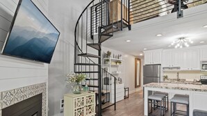 Une cuisine moderne dotée d’un îlot central, d’une cheminée et d’un escalier en colimaçon.