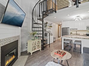 Eine moderne Küche mit Kochinsel, Kamin und Wendeltreppe.