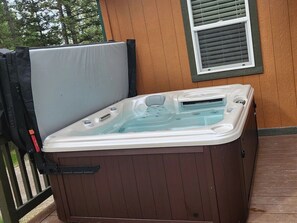 A hot tub on a wooden deck with a window and a door. - Life's a Bear Haven!!  Couple's Hot Tub under the Sky!  King Bed! (Kalispell)