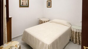 Una camera da letto con un letto, due comodini, un tavolino rotondo e due quadri appesi al muro.