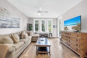 Un salon avec un canapé, une table basse et un téléviseur posé sur un meuble en bois.