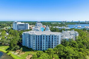 A multi-story hotel with a central courtyard, surrounded by lush greenery and a marina with boats. - Resort Amenities-Ground Floor-Walk To Baytowne Wharf-E5109 (Miramar Beach)