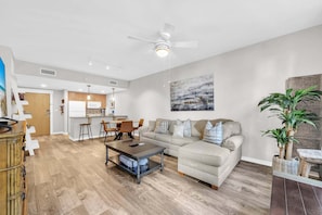 A modern living room with a sofa, coffee table, and a dining area with chairs. - Resort Amenities-Ground Floor-Walk To Baytowne Wharf-E5109 (Miramar Beach)