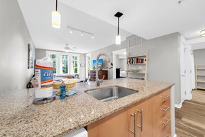 Eine moderne Küche mit Granit Arbeitsplatten, einer Edelstahl-Spüle und Holzschränken.