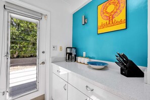 A kitchen with a white countertop, a coffee maker, a bowl, and a knife block. - Meiselman Palms - A Ryson Property (Palm Springs)