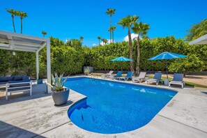 A swimming pool with lounge chairs and umbrellas, surrounded by palm trees and a pergola. - Meiselman Palms - A Ryson Property (Palm Springs)