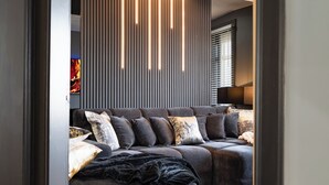 Una sala de estar moderna con un sofá, almohadones y una pared con líneas verticales e iluminación.