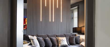 A modern living room with a sofa, pillows, and a wall with vertical lines and lighting.