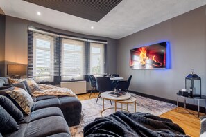 A modern living room with a sofa, a coffee table, and a TV mounted on the wall.