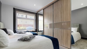 Un dormitorio moderno con una cama grande, un armario y una ventana con persianas.