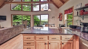 A spacious kitchen with a large island, wooden cabinets, and a view of the outdoors. - Charming 4BR Cabin - HOT TUB - Mountain View (Oakland)