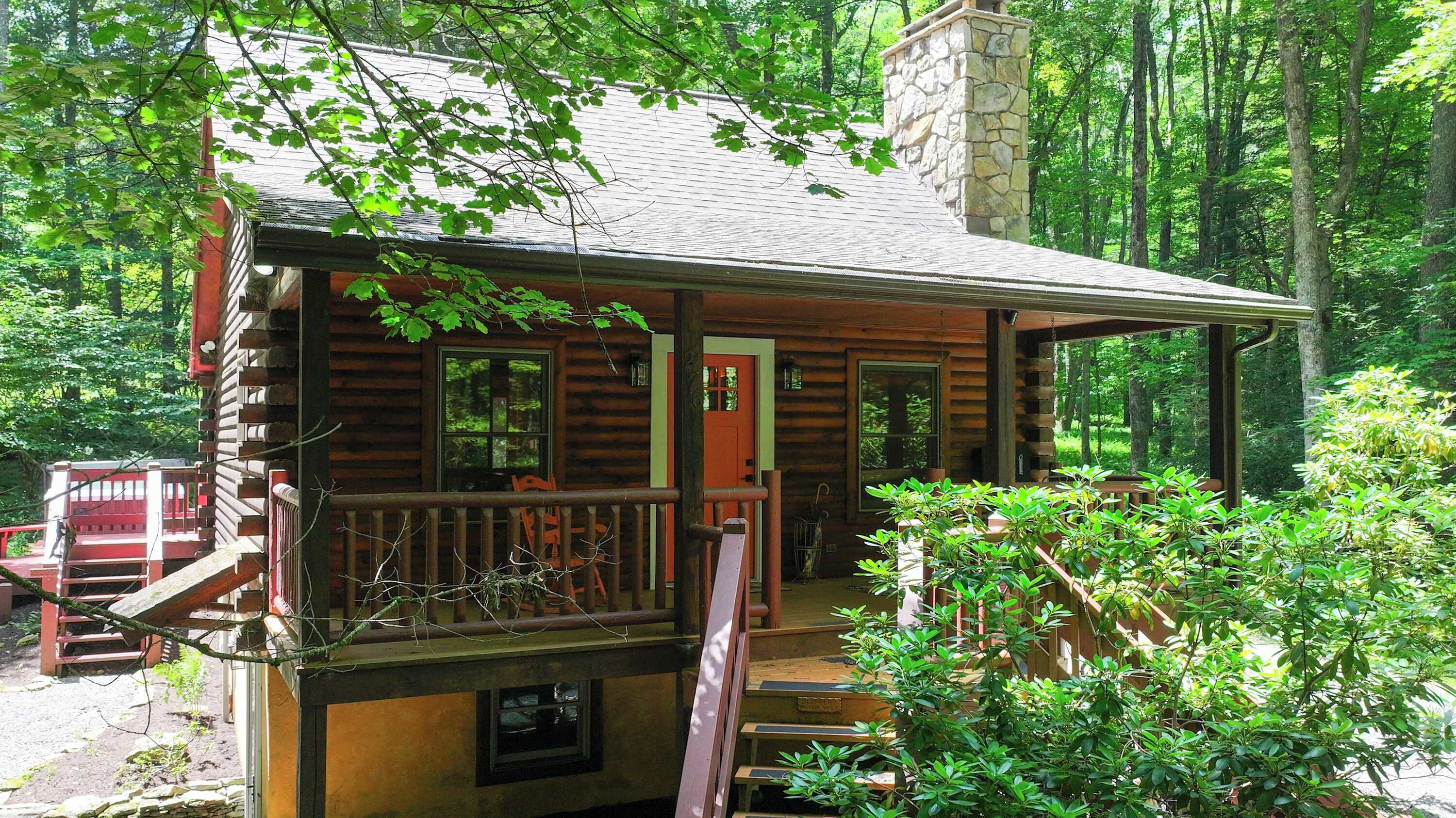 A log cabin with a porch, a chimney, and a small window.