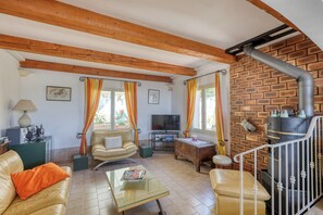 Ein Wohnzimmer mit Fernseher, Ledersofa, Glastisch und Kamin mit Schornstein.