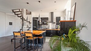 A modern kitchen with a wooden dining table and chairs, a staircase, and a potted plant. - Loft Arrousets - Welkeys (Bayonne)
