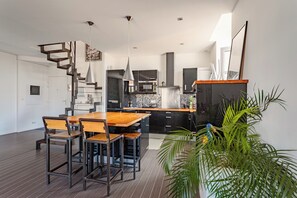 Eine moderne Küche mit einem Holzespeisetisch und Stühlen, einer Treppe und einem Blumentopf.