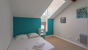 A bedroom with a skylight, a bed, a white radiator, and a tiger painting on the wall. - Loft Arrousets - Welkeys (Bayonne)