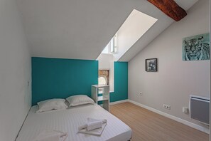 Ein Schlafzimmer mit Dachfenster, einem Bett, einem weißen Heizkörper und einem Tigergemälde an der Wand.