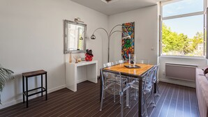 A modern dining area with a wooden table and clear chairs, a white console table with decorative items, a large mirror, and a colorful artwork on the wall. - Loft Arrousets - Welkeys (Bayonne)