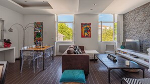 A modern living room with a dining area, a fireplace, and a stone wall. - Loft Arrousets - Welkeys (Bayonne)
