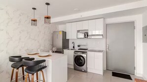 A modern kitchen with a central island, a built-in washing machine, and a refrigerator. - 906 Sky Garden (San José)