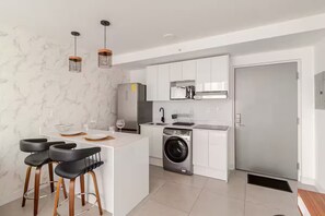 Eine moderne Küche mit einer zentralen Kochinsel, einer integrierten Waschmaschine und einem Kühlschrank.