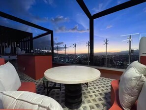 A high-rise room with a round table and chairs, a city view, and a red accent wall. - 906 Sky Garden (San José)