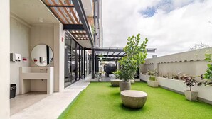 A rooftop terrace with artificial grass, potted plants, and a modern architectural design. - 906 Sky Garden (San José)