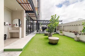 Eine Dachterrasse mit künstlichem Rasen, Topfpflanzen und modernem architektonischem Design.