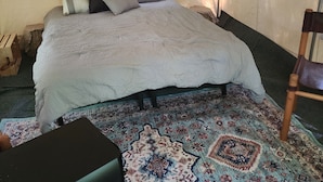 Ein Zelt mit Bett, Fenster und einem gemusterten Teppich.