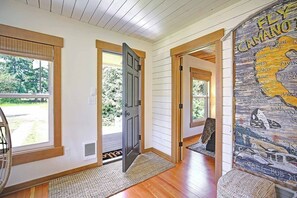 A hallway with wooden floors, a door leading to an outdoor area, and a wall with a nautical-themed mural.