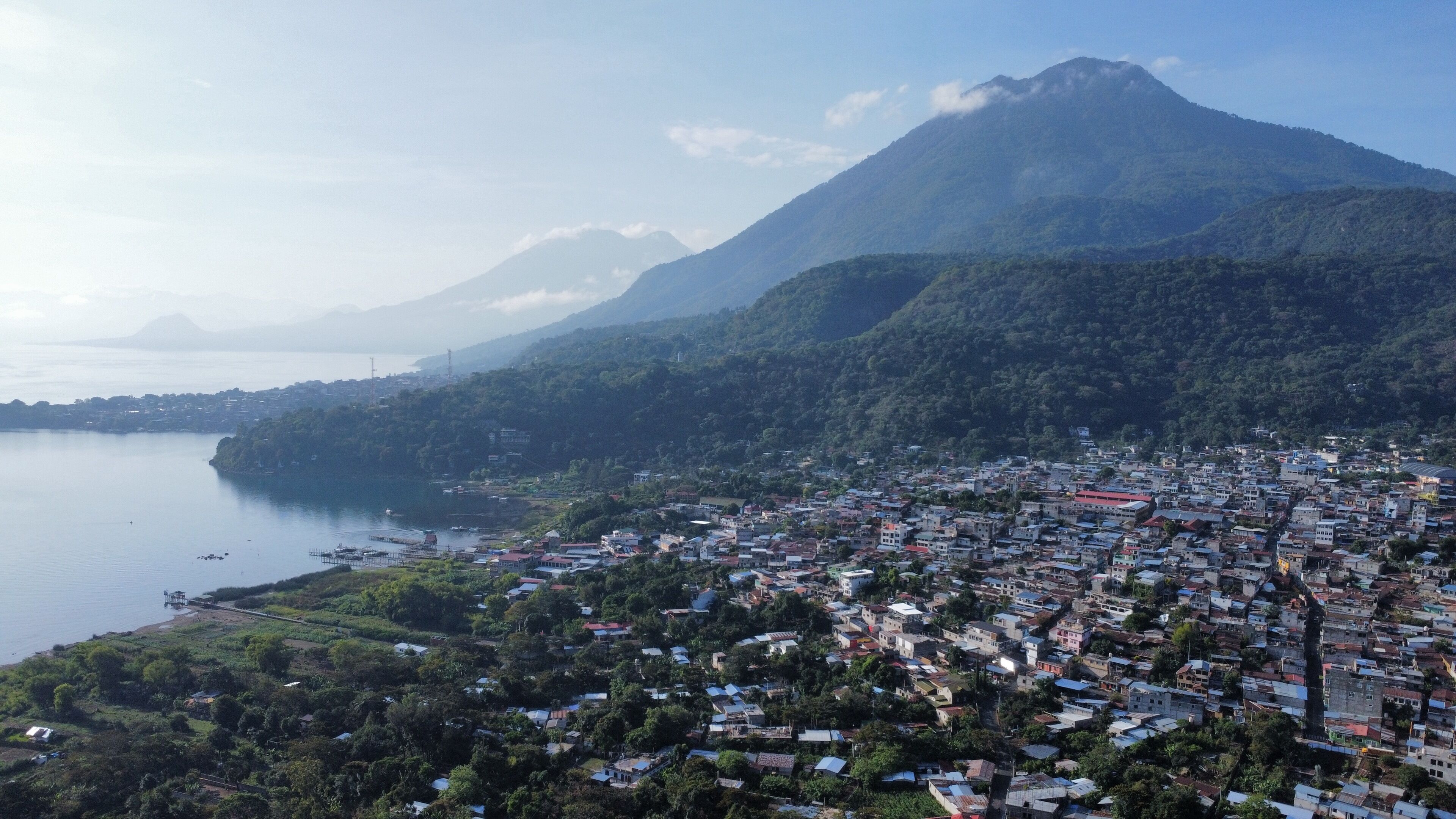 A coastal town with a mountain in the background, houses, and a body of water.