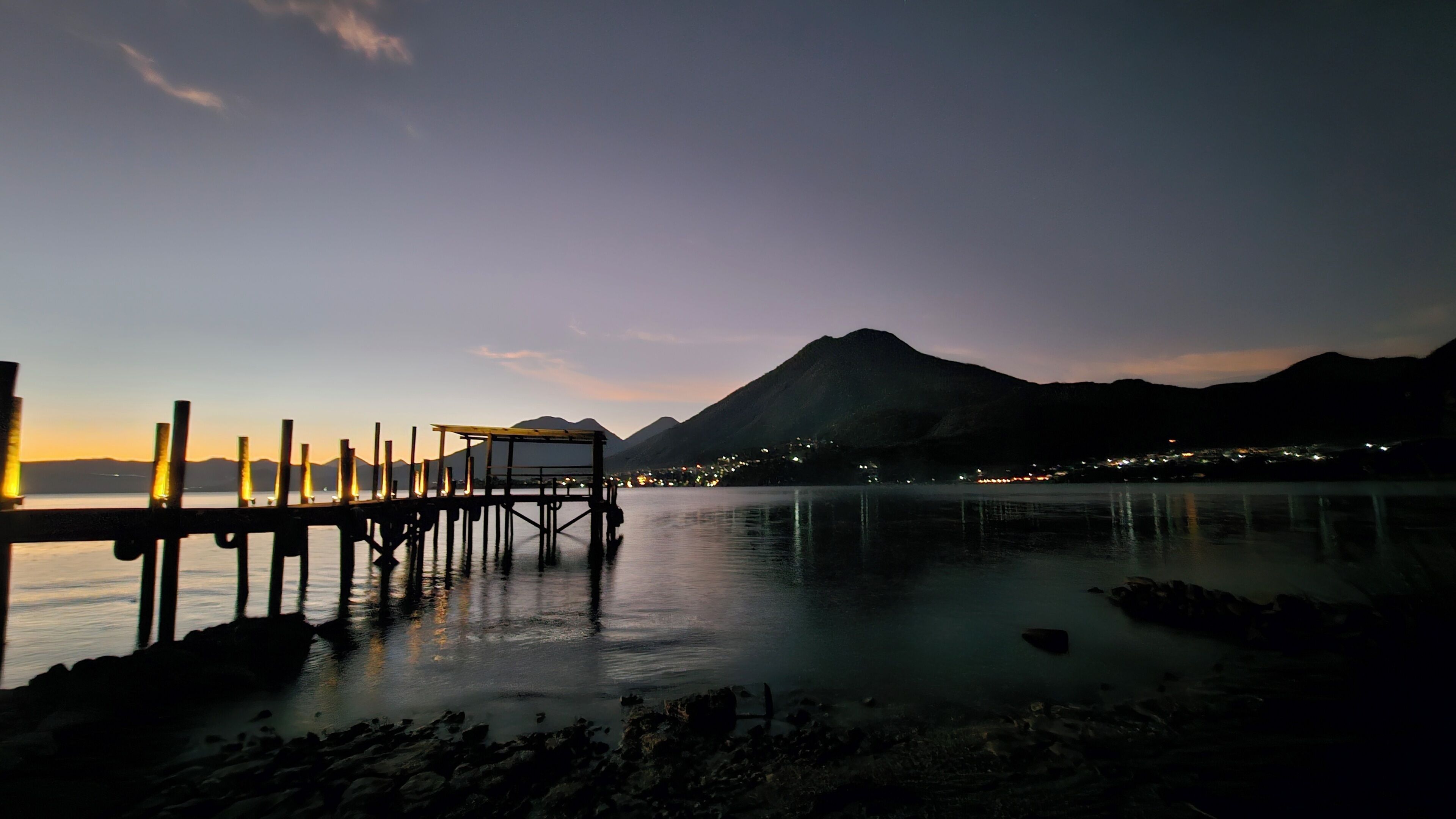 A pier extending into calm waters with a mountain in the background.