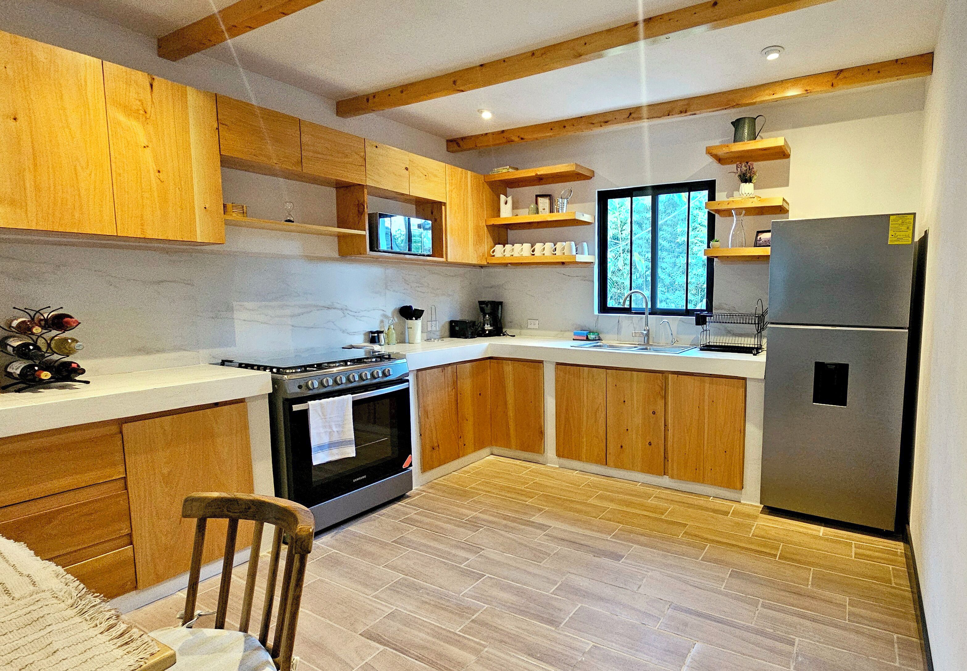 Una cocina moderna con armarios de madera, un refrigerador de acero inoxidable y un horno empotrado.