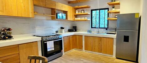 Una cocina moderna con armarios de madera, un refrigerador de acero inoxidable y un horno empotrado.