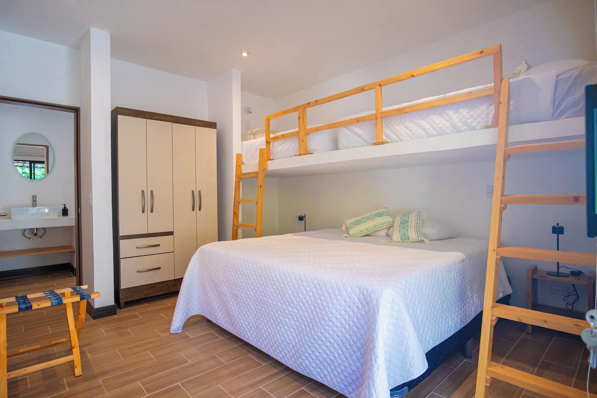 Habitación con literas, una escalera de madera, mesita de noche y armario.