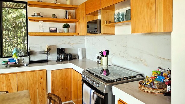 A modern kitchen with wooden cabinets, a gas stove, and a built-in oven.