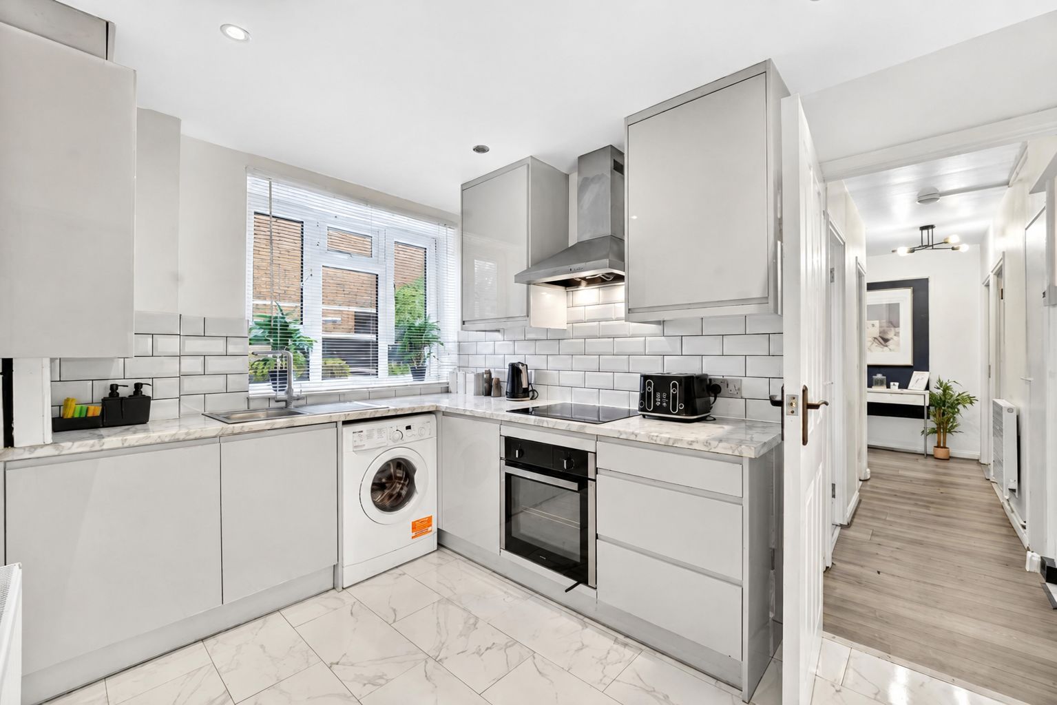 A modern kitchen with white cabinetry, a built-in washing machine, and a stove.