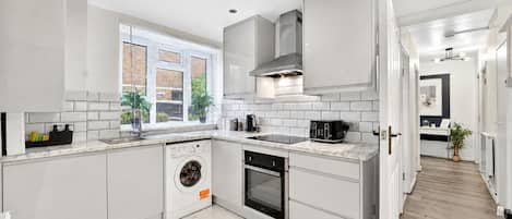 A modern kitchen with white cabinetry, a built-in washing machine, and a stove.