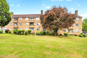 A multi-story residential building with a flat roof, multiple windows, and a well-maintained lawn in front. - Family-friendly 2-bed apartment near station, sleeps 5 (London)