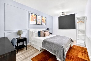 Une chambre moderne avec un lit, une table de chevet, une lampe et un téléviseur fixé au mur.