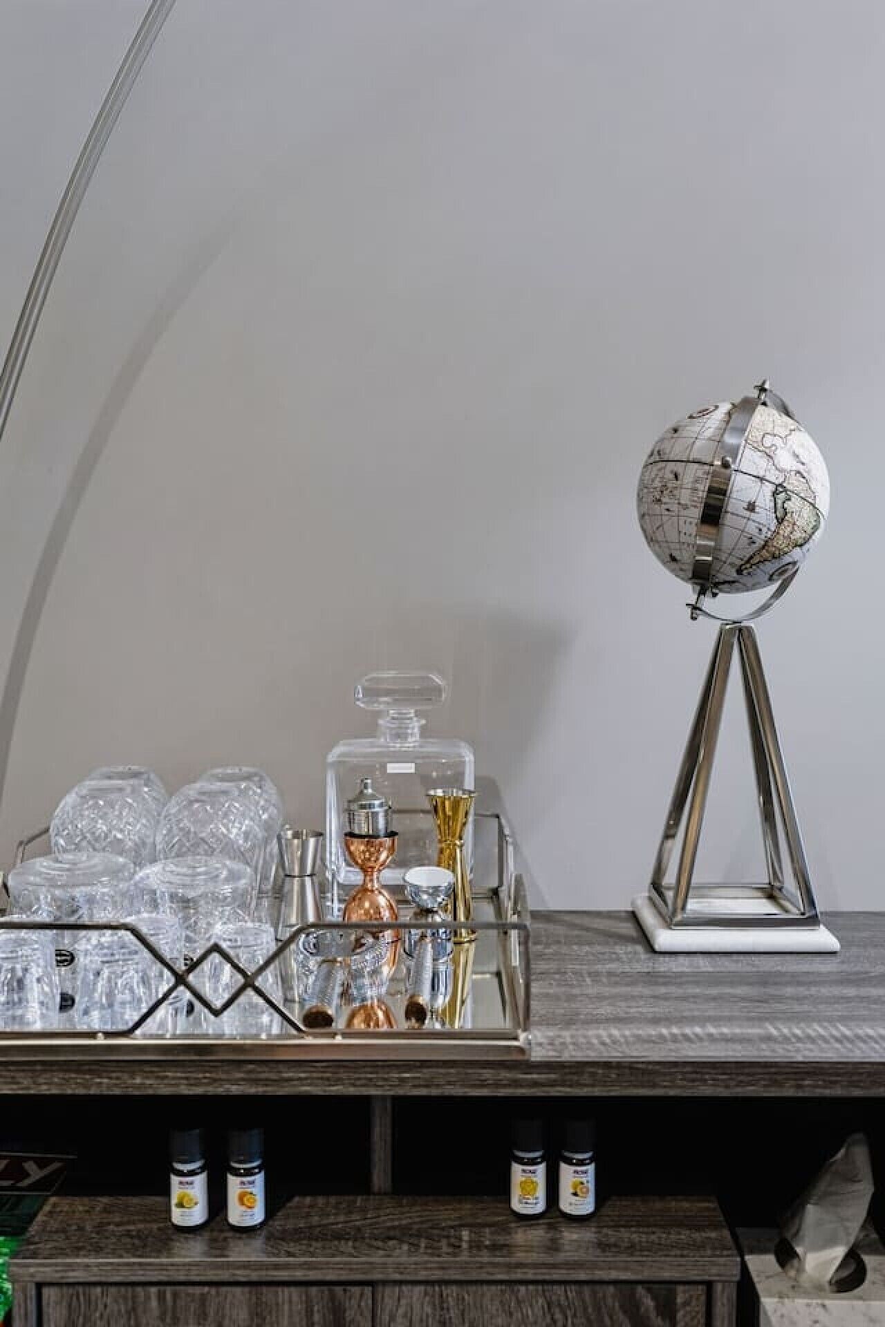 A wooden table with a globe, a tray with glassware, and bottles.