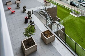 A rooftop terrace with seating, planters, and a view of the street. - The Knox | Central Pet-Friendly Kelowna 2BR Condo (Kelowna)