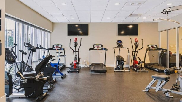 A gym with various exercise equipment including treadmills, stationary bikes, and elliptical machines. - The Knox | Central Pet-Friendly Kelowna 2BR Condo (Kelowna)